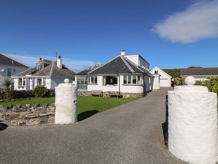 A house with a driveway and a lawn with benches at Angorfa Trearddur Bay