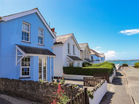 A row of houses by a street with a view of the sea at Arkoo in Rhosneigr