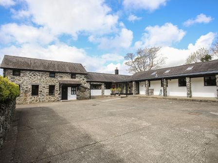 A courtyard with stone and white buildings under a blue sky at Bryn Eira Stables in Llanfair PG