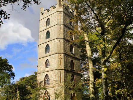 A stone tower with arched windows surrounded by trees at Brynkir Tower in Garndolbenmaen