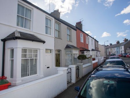 A street with terraced houses and parked cars along the sidewalk at Bro Dawel in Beaumaris