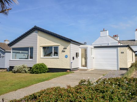 A single-story house with a driveway and a garden with bushes at Flip Flops in Rhosneigr