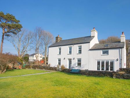 A white two-story house with chimneys and a green lawn with trees at Big House in Llandecwyn