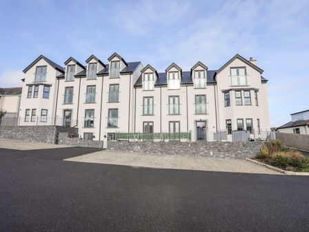 A multi-story white residential building with multiple windows and balconies in Puffin Pad Benllech