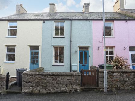 A row of three connected houses with stone walls and blue doors at 14 Rose Hill in Beaumaris