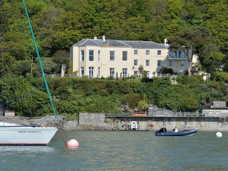 A house on a hill with boats in the water at Tan Y Coed in Menai Bridge