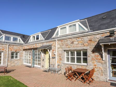 A stone exterior of a building with windows and doors and outdoor seating at Tyn Towyn - Ty Melyn in Trearddur Bay