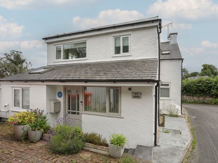 The exterior of a white two story house with plants in pots near the entrance at Ty Mawr in Llandegfan