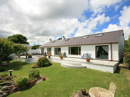 A house with a patio garden and outdoor furniture at Ty'n Cae in Red Wharf Bay