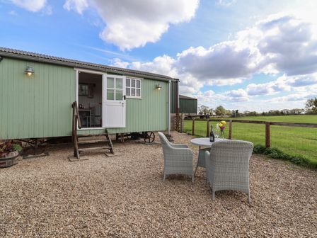 A shepherd hut with a seating area outside at The Shepherds Hut in Chippenham