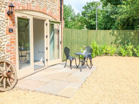 A patio with two black metal chairs and a small round table outside a building with a stone and brick exterior at The Cart Shed in Willow Grange Barns Stanfield