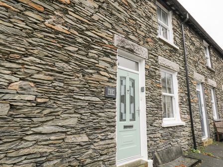 Stone exterior wall with a green door and windows at St Marys Cottage in Windermere