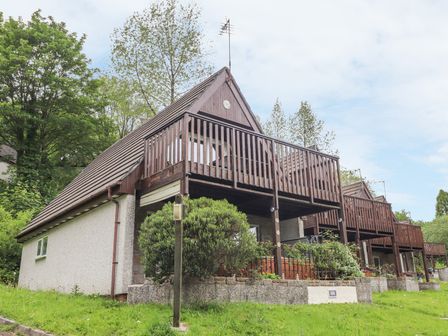 A row of houses with wooden balconies and a grassy lawn at Valley Lodge 52 in Callington