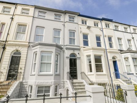 A row of white and light grey terraced houses with black and blue doors and iron railings at Station House in Scarborough