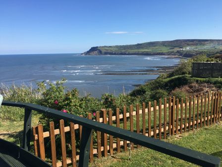 A coastal view with a wooden fence and greenery overlooking the sea at 2 The Close in Robin Hood'S Bay