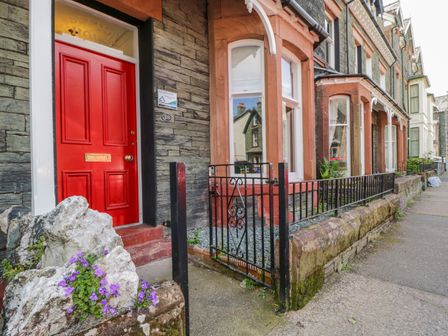 A row of stone houses with a red door and black metal gate at Sefton House in Keswick