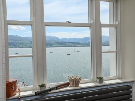 A window with a view of water and sailboats with decorative items on the windowsill at Gadlys House - Beau View in Beaumaris