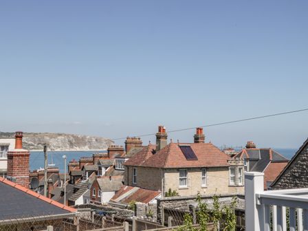 A view of rooftops with chimneys and a cliff by the sea at Seaview in Swanage