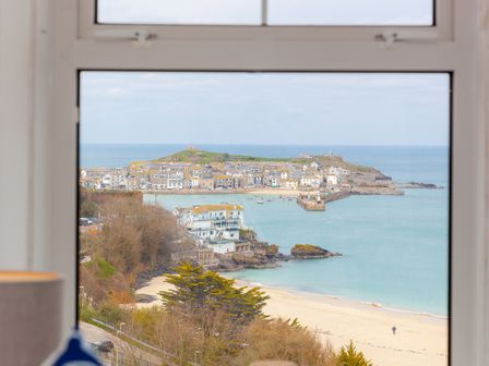 A coastal town with buildings and boats near a sandy beach viewed through a window at Trevose in St Ives