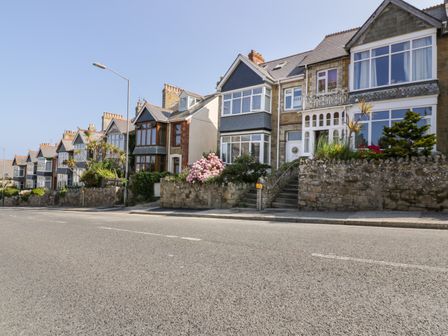 A row of stone and brick houses with front gardens and steps along a street at Seascape in Newquay