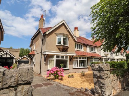 A row of attached houses with a gravel garden and pink flowers by the entrance at Park View in Llandudno