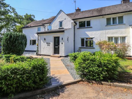 White exterior of a house with a black door pathway and green shrubs at Ellerbeck Bridge Underbarrow near Kendal