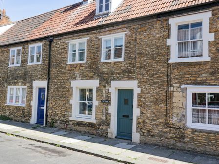 A street view of stone cottages with blue doors and white window frames at Troopers Cottage in Frome