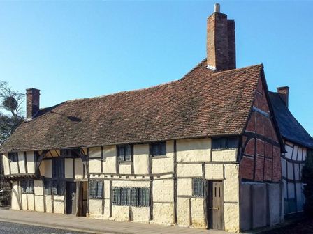 An old timber framed house with a tiled roof and multiple chimneys at 3 Masons Court in Stratford-Upon-Avon