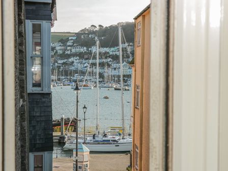 A view of sailboats docked at a marina between buildings with houses on a hillside in the background at Walters Rest in Dartmouth