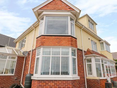A house exterior with bay windows and red brick lower walls at The Gansey Girl in Bridlington