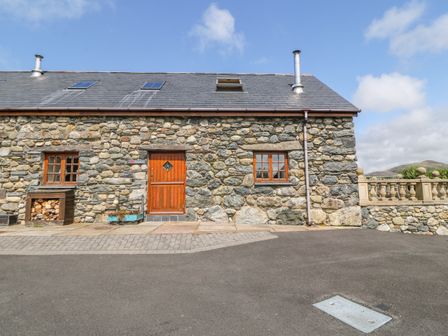 A stone building with a wooden door and two windows under a slate roof at Dysynni in Bryncrug near Tywyn