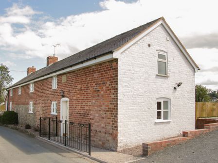 A brick and whitewashed house with multiple windows and a black metal fence at Conquer Hall in Hendomen near Montgomery