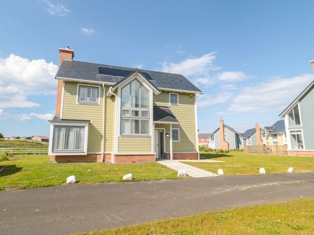 A detached house with large windows and solar panels on the roof at Waterside in Beadnell