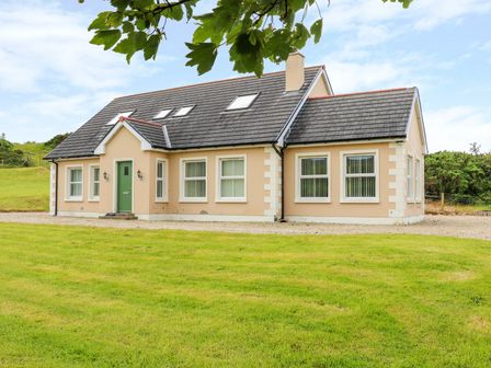 A detached house with beige walls green door grey roof and lawn in front at Croghan in Portsalon