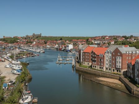 A harbor with boats docked and buildings alongside the water at Marina Apartment in Whitby