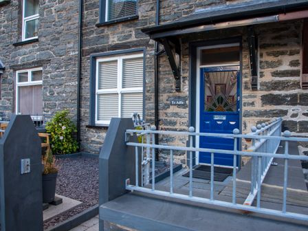 A stone exterior of a building with a blue door and metal gate at Yr Adfa The Retreat in Blaenau Ffestiniog