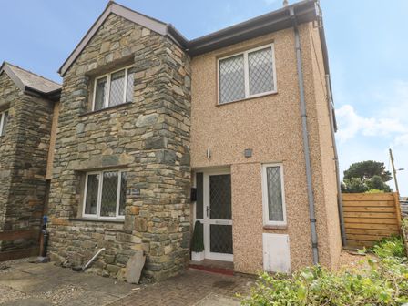 An exterior view of a two story house with stone and pebble dash walls and diamond patterned windows at 4 Ty Rhosyn in Morfa Bychan