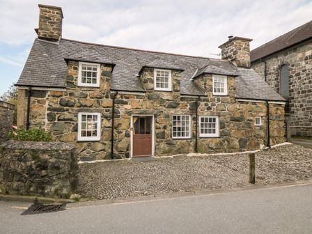 A stone cottage with a slate roof and several windows on a cobblestone driveway at Fro Awel in Dolgellau