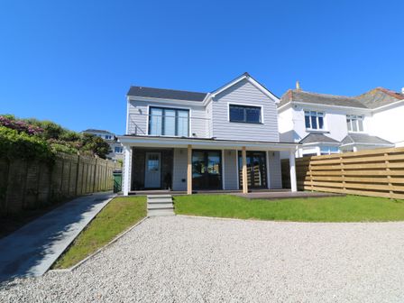 A two-story house with a gravel driveway and grass lawn at Driftwood Haven in Carbis Bay