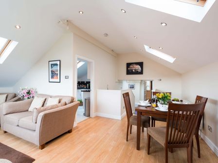 A dining table with four chairs and a sofa in a room with skylights at Fishermans Warehouse in Whitby