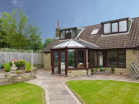 A house with a conservatory and a garden with grass and plants at Seawinds in Robin Hood'S Bay