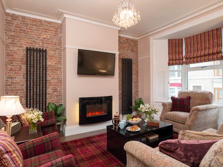 A living room with plaid armchairs a fireplace a television and a coffee table with food at See Glympse in Whitby