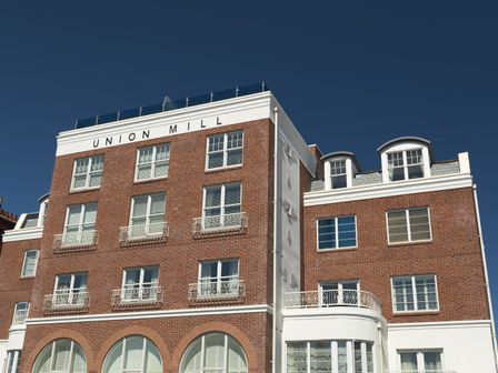 A multi-story brick building with multiple windows under a clear sky at Union Mill