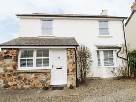 A stone and white exterior house with a white front door and windows with blinds at Ty'r Winllan in Newport Pembrokeshire