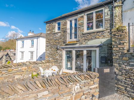 A stone cottage with a small outdoor seating area and a black gate in front at Prospect Cottage Studio Ambleside