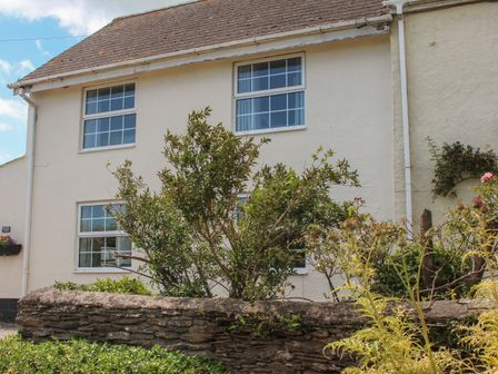 A stone wall with plants in front of a two-story house with four windows at Little Piccadilly in Cole's Cross near Kingsbridge