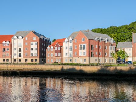 A waterfront view of modern apartment buildings with reflections in the water at Quayside Haven in Whitby