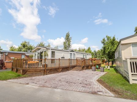 A residential park home with a wooden deck and paved driveway surrounded by trees at Ramblers Rest in Felton