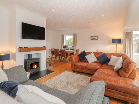 A living room with sofas a fireplace a dining table and chairs at Nefydd in Criccieth
