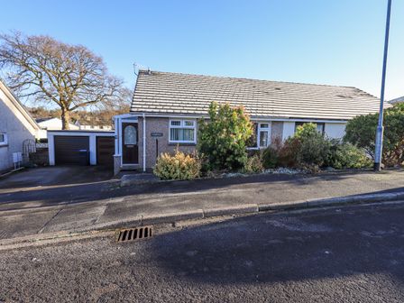 A bungalow house with a driveway garage and shrubs in front at Fairfell in Keswick